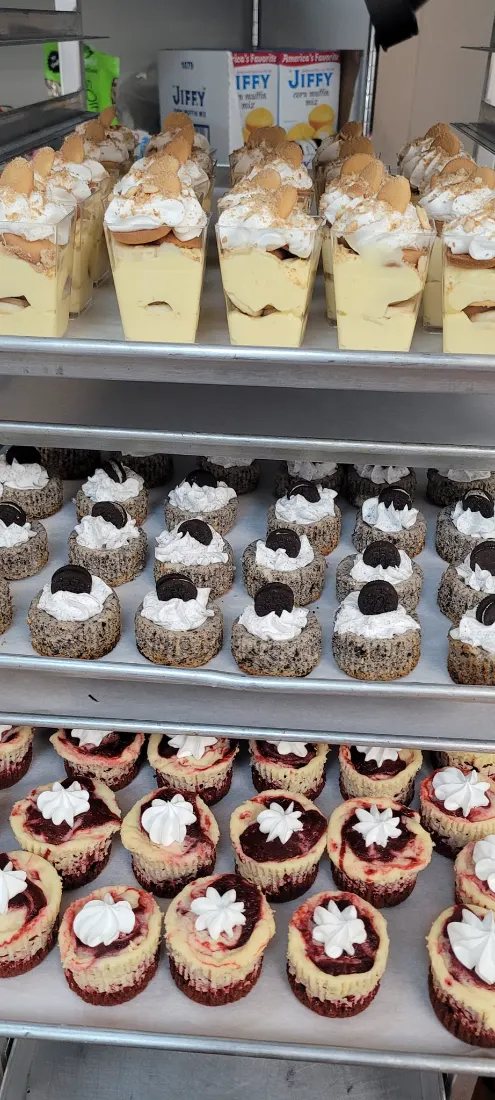 Racks of individual dessert cups and red velvet cakes topped with piped cream